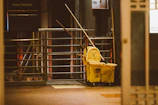 yellow plastic trash bin beside black metal stair railings