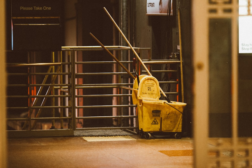 yellow plastic trash bin beside black metal stair railings