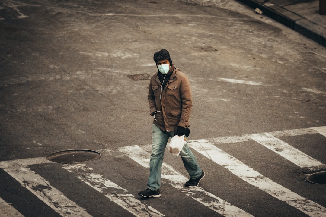 man in brown jacket and gray pants walking on road during daytime