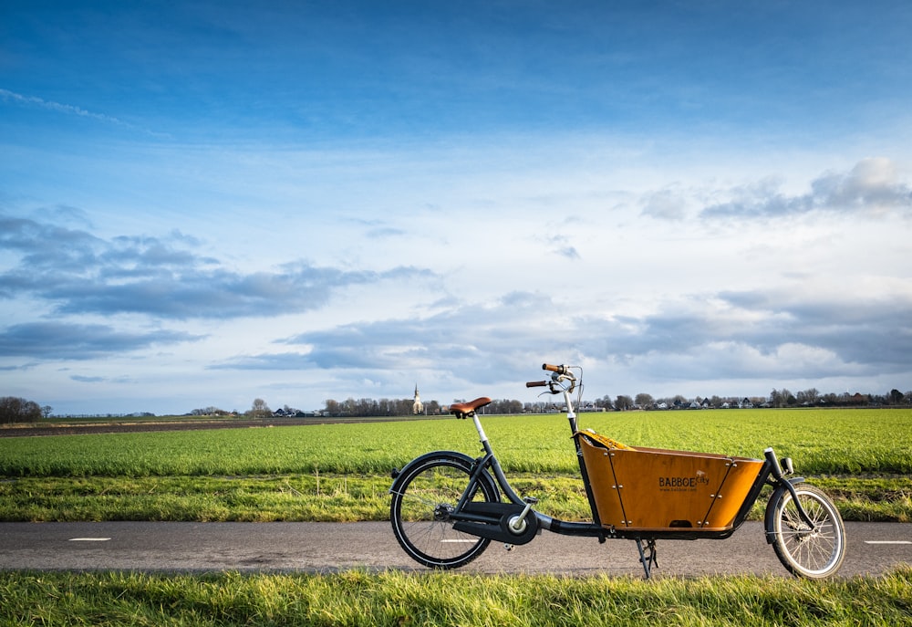 yellow and black bicycle on green grass field under blue sky during daytime