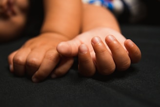 Close-up of intertwined hands resting gently on bare skin.