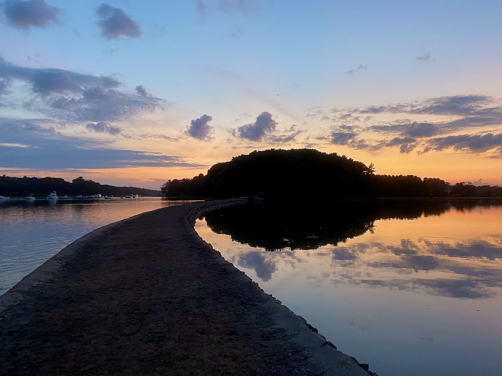 body of water near trees during sunset