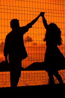A couple holding hands warmly during a sunset, symbolizing emotional reconnection.