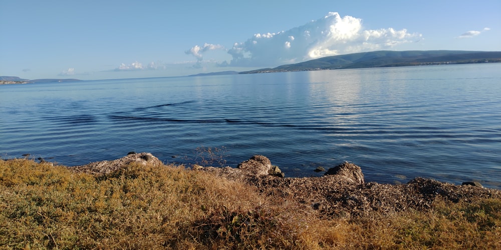 body of water near mountain under blue sky during daytime