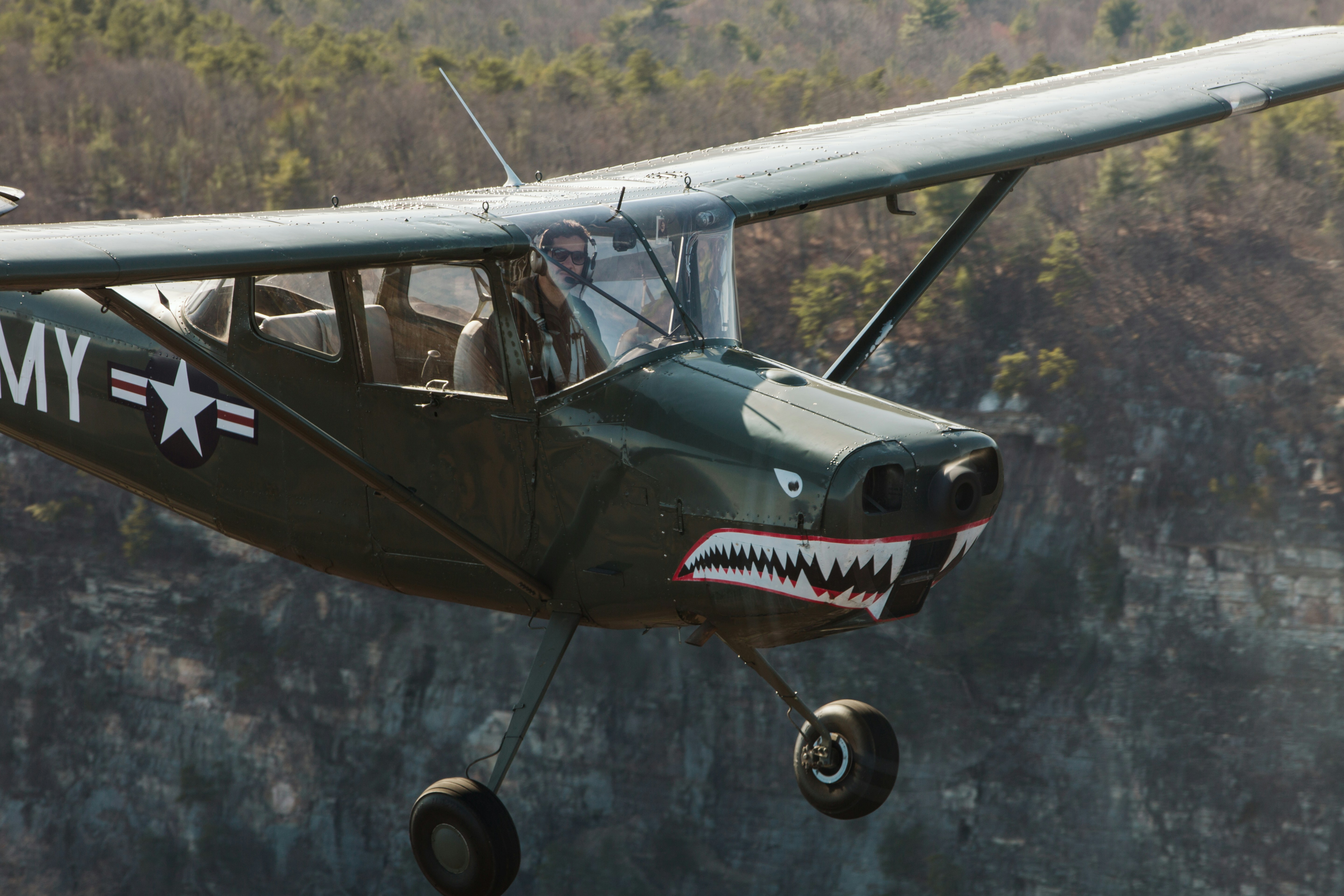 black and white airplane on mid air during daytime, L-19 flying along cliffs