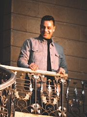 A smiling inspector examining a sunlit balcony with a notebook in hand