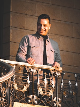 A smiling inspector examining a sunlit balcony with a notebook in hand