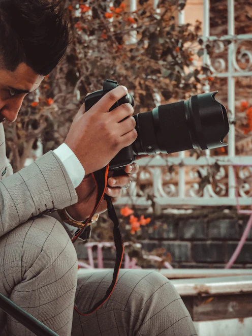 man in gray long sleeve shirt holding black dslr camera