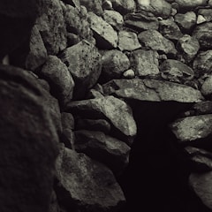 A collection of rough, uneven stones stacked together in a natural formation, creating a textured surface. The stones vary in size and shape, with an overall earthy appearance.