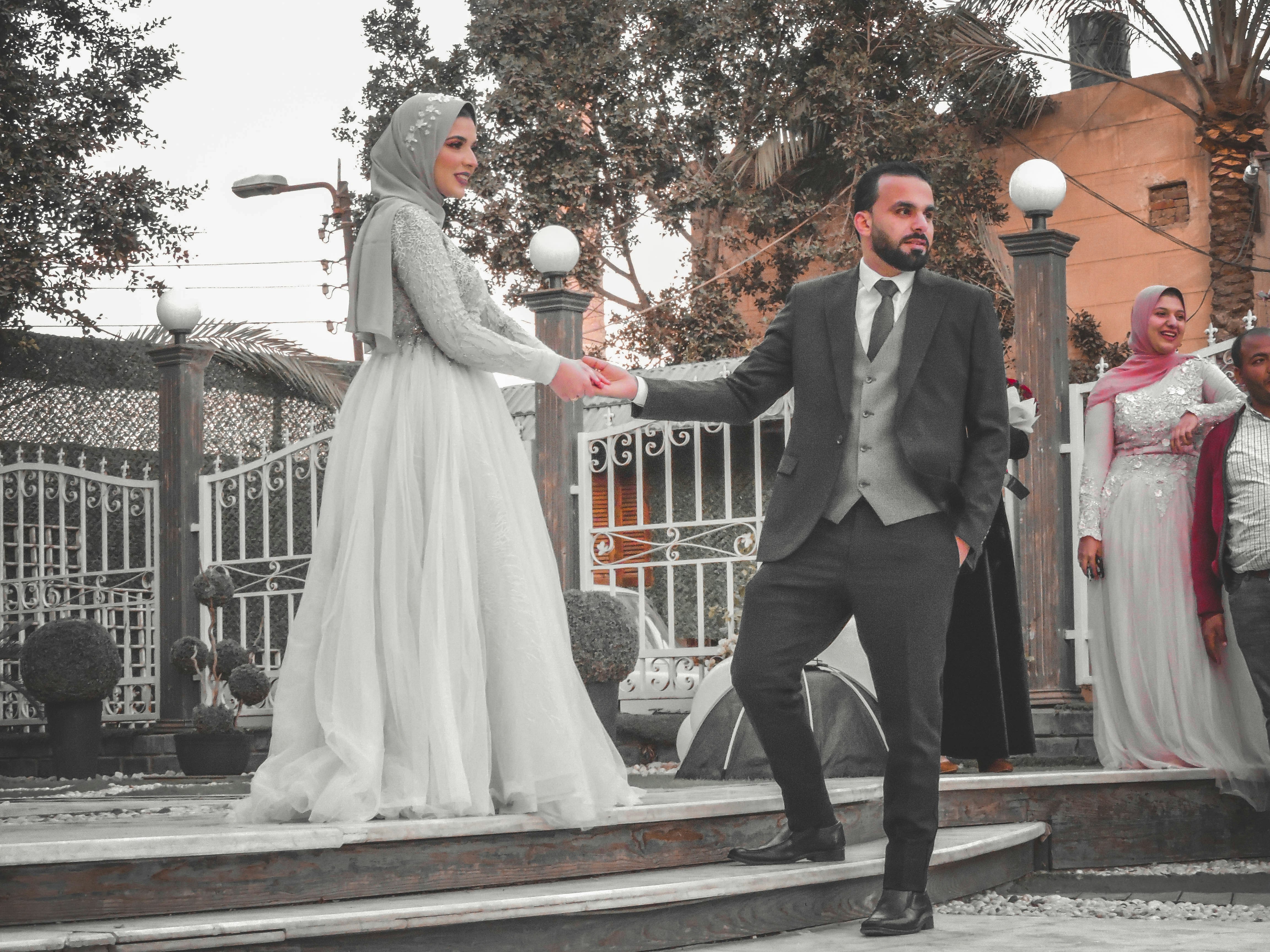 man in black suit standing beside woman in white wedding dress