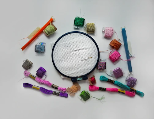 Tools of the trade: wooden embroidery hoops, silk threads, and delicate needles arranged on a wooden table.