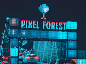A futuristic and vibrant setting featuring a large sign with the words 'PIXEL FOREST' illuminated in neon colors. Below the sign, cars are passing through a tunnel-like structure with digital and geometric design elements. The overall atmosphere is immersive and bright, enhanced by blue and red lighting.
