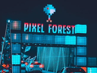 A futuristic and vibrant setting featuring a large sign with the words 'PIXEL FOREST' illuminated in neon colors. Below the sign, cars are passing through a tunnel-like structure with digital and geometric design elements. The overall atmosphere is immersive and bright, enhanced by blue and red lighting.