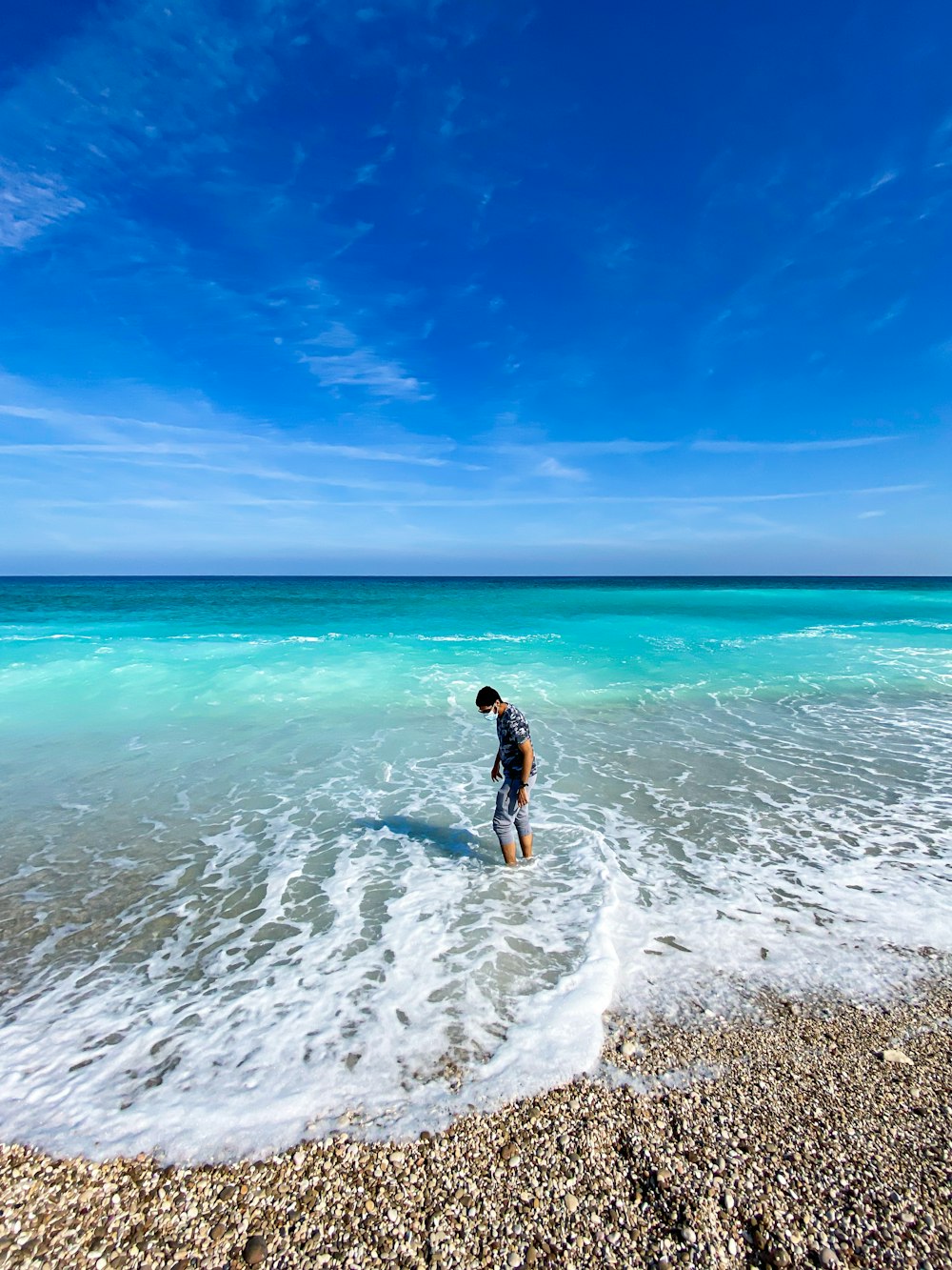 woman in black dress walking on beach during daytime