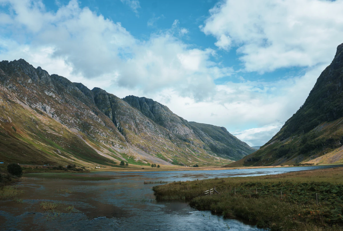 Glencoe valley with green mountains and river under blue sky