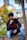 man in black long sleeve shirt and blue denim jeans sitting on brown wooden post during