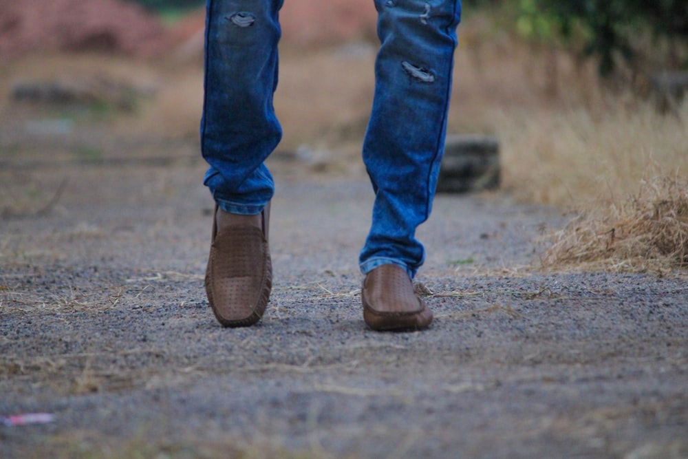 person in blue denim jeans and brown leather boots