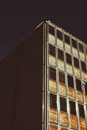 A sleek modern building facade showcasing aluminum and wood elements under bright daylight.