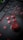 A close-up of a gaming joystick with red buttons marked A, B, X, and Y. The joystick is placed on top of a laptop keyboard, with keys outlined in red. The image is dimly lit, enhancing the contrast between the red components and the dark background.