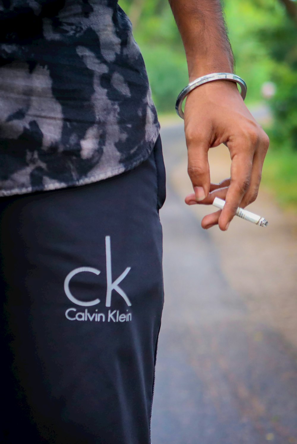 person in black and white shirt holding cigarette stick