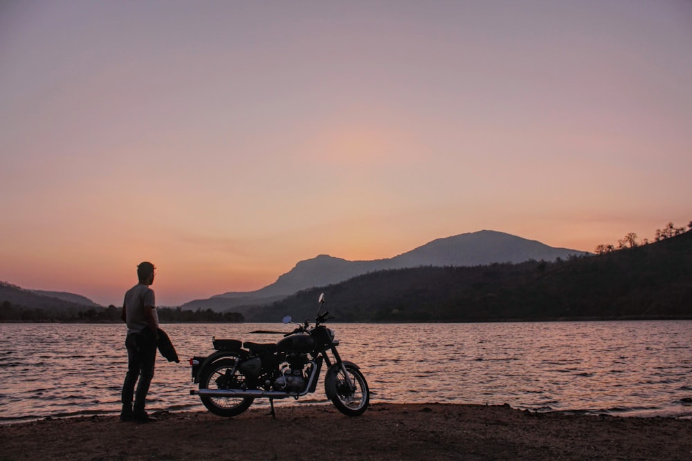 man and woman standing beside motorcycle near body of water during daytime