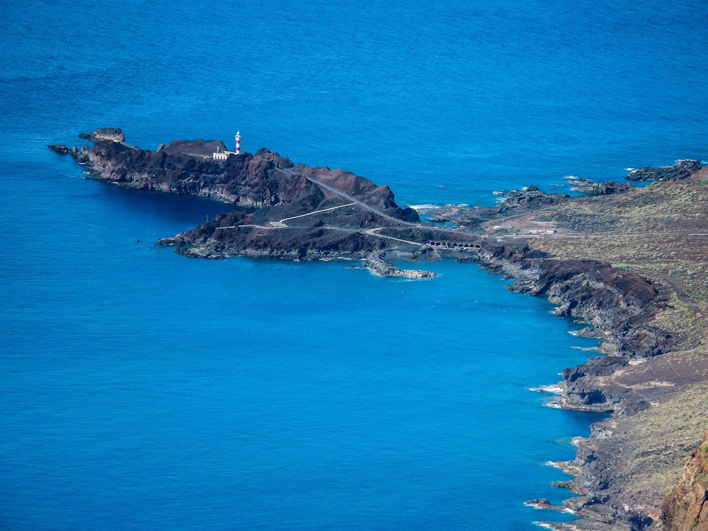 person standing on rock formation in front of blue sea during daytime