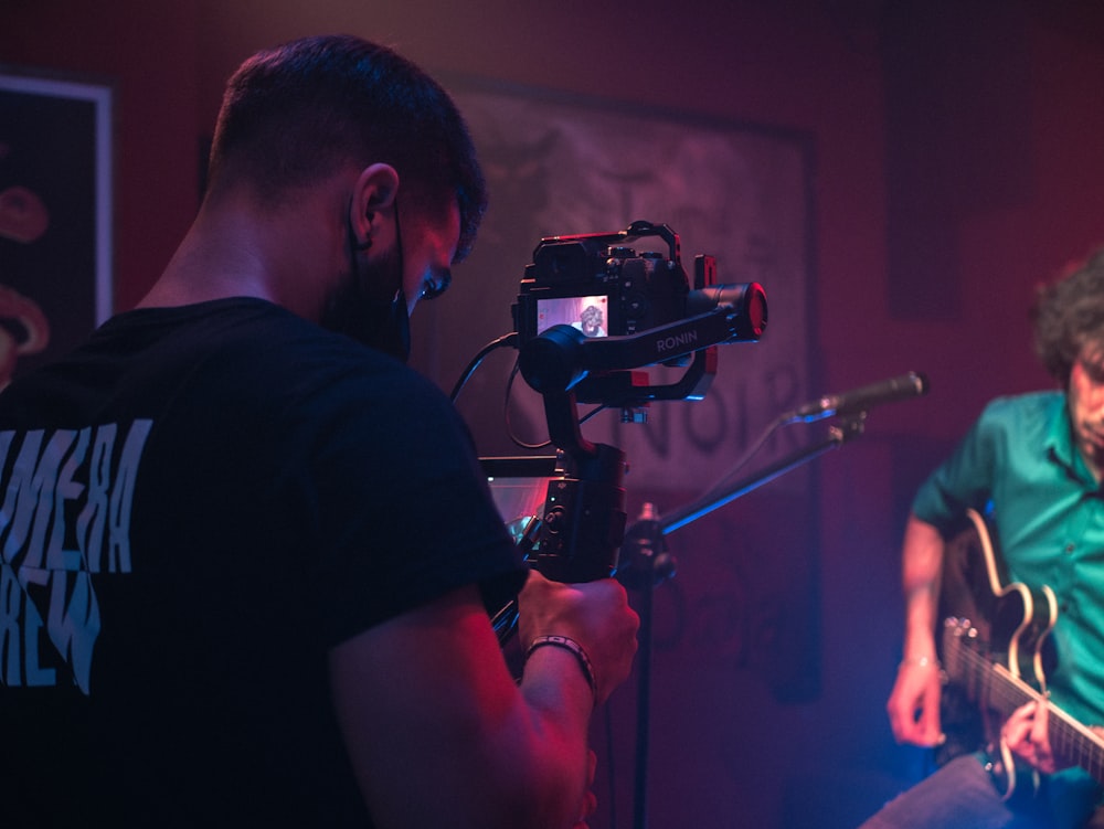 man in black t-shirt holding black video camera