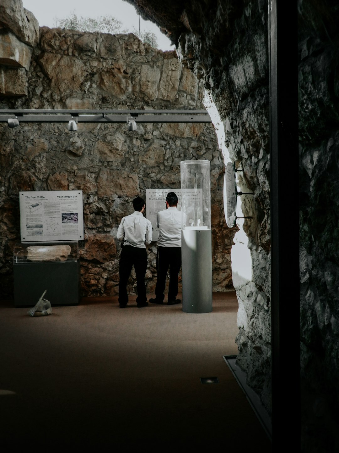 man in white dress shirt and black pants standing beside white plastic trash bin