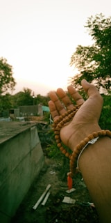 Manos sosteniendo amuletos y símbolos ancestrales bajo la luz del sol poniente.