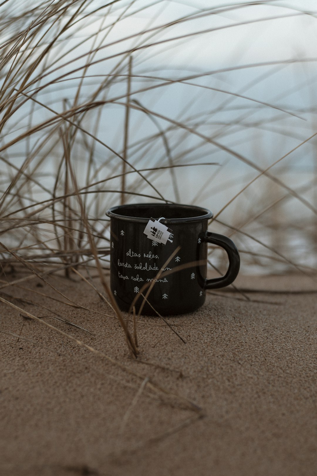 black ceramic mug on brown sand