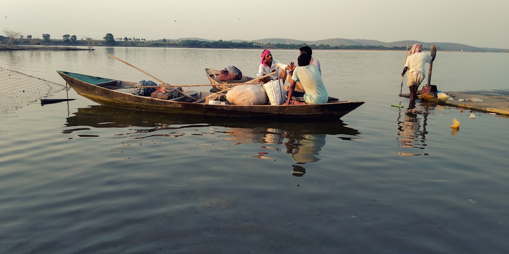 3 men riding on brown boat on water during daytime