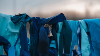 A serene display of blue dhotis hanging gently against a backdrop of deep peacock green.