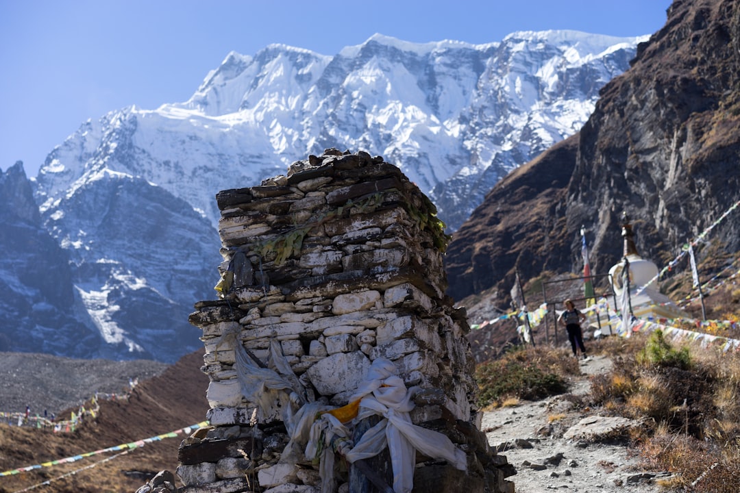 person in yellow jacket standing on rocky mountain during daytime