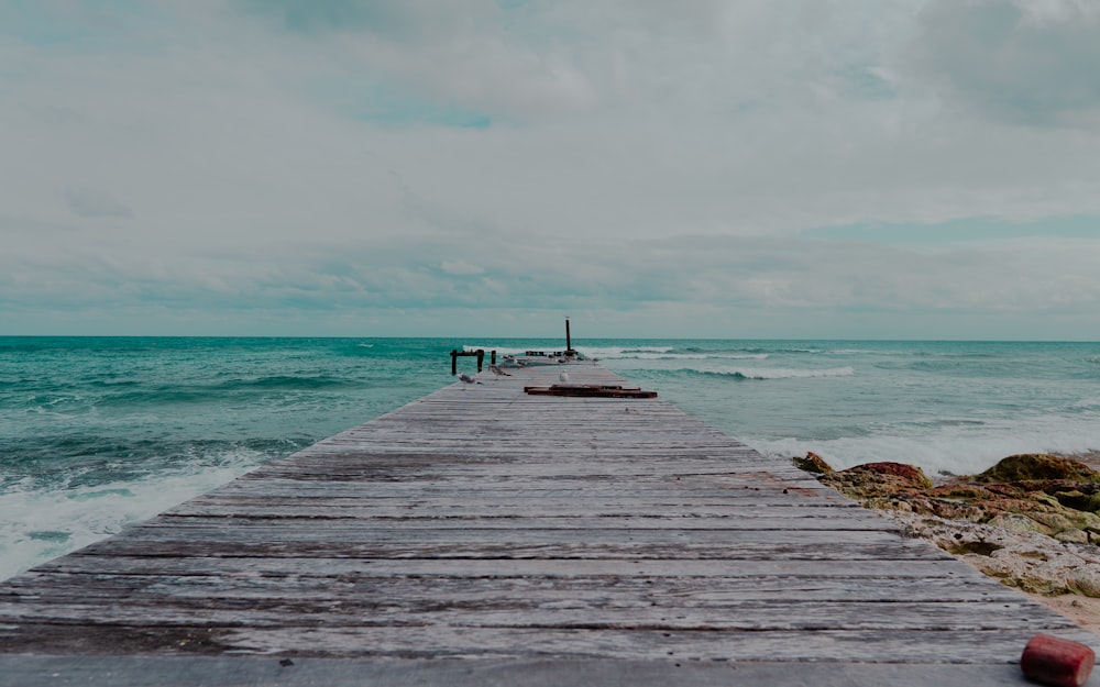 person standing on wooden dock near sea during daytime