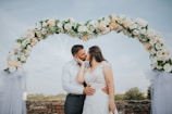 A bride and groom sharing a tender kiss under a blooming archway.