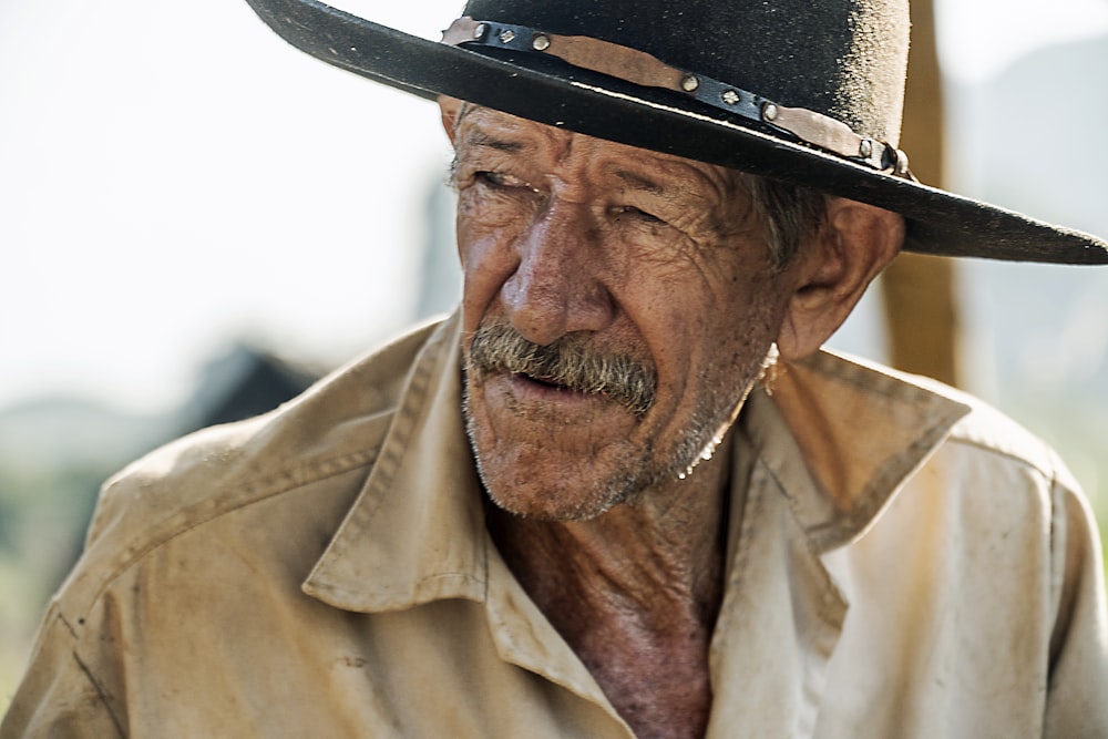 man in beige button up shirt wearing black fedora hat