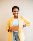 smiling woman in yellow blazer holding tablet