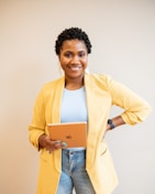 woman in yellow blazer and blue denim jeans smiling
