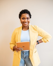 black woman in yellow blazer and blue denim jeans smiling