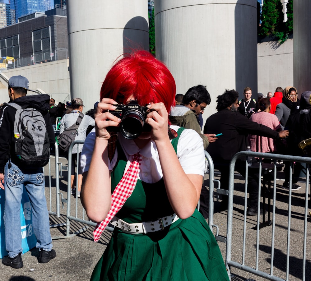 黒いデジタル一眼レフカメラを持つ緑のドレスを着た女性