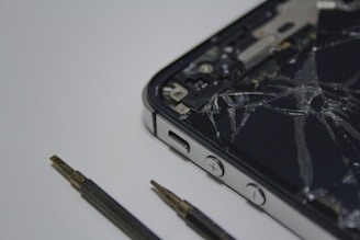 Close-up of a technician carefully replacing a cracked smartphone screen with precision tools on a workbench.
