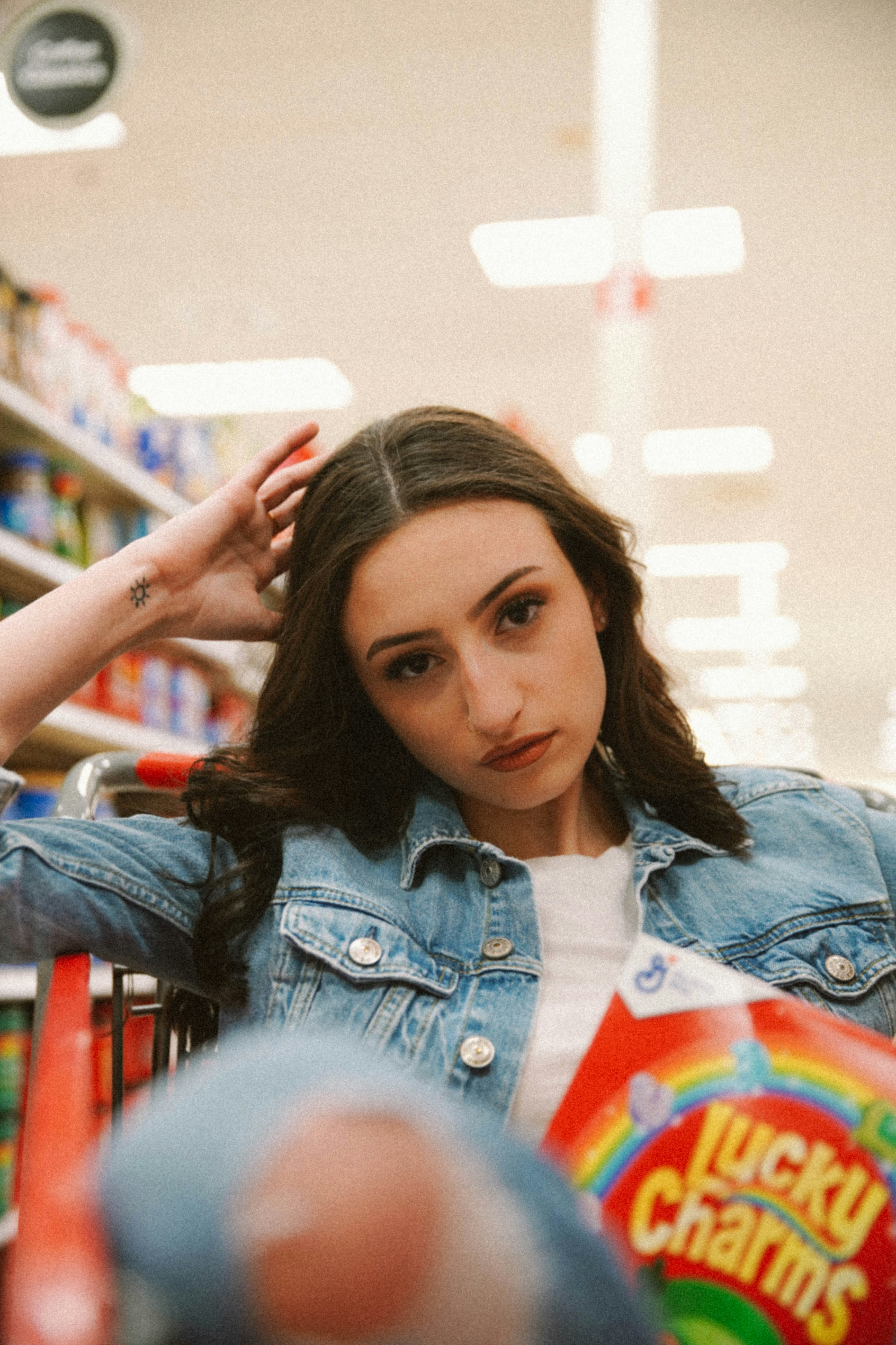 woman in blue denim jacket holding her hair