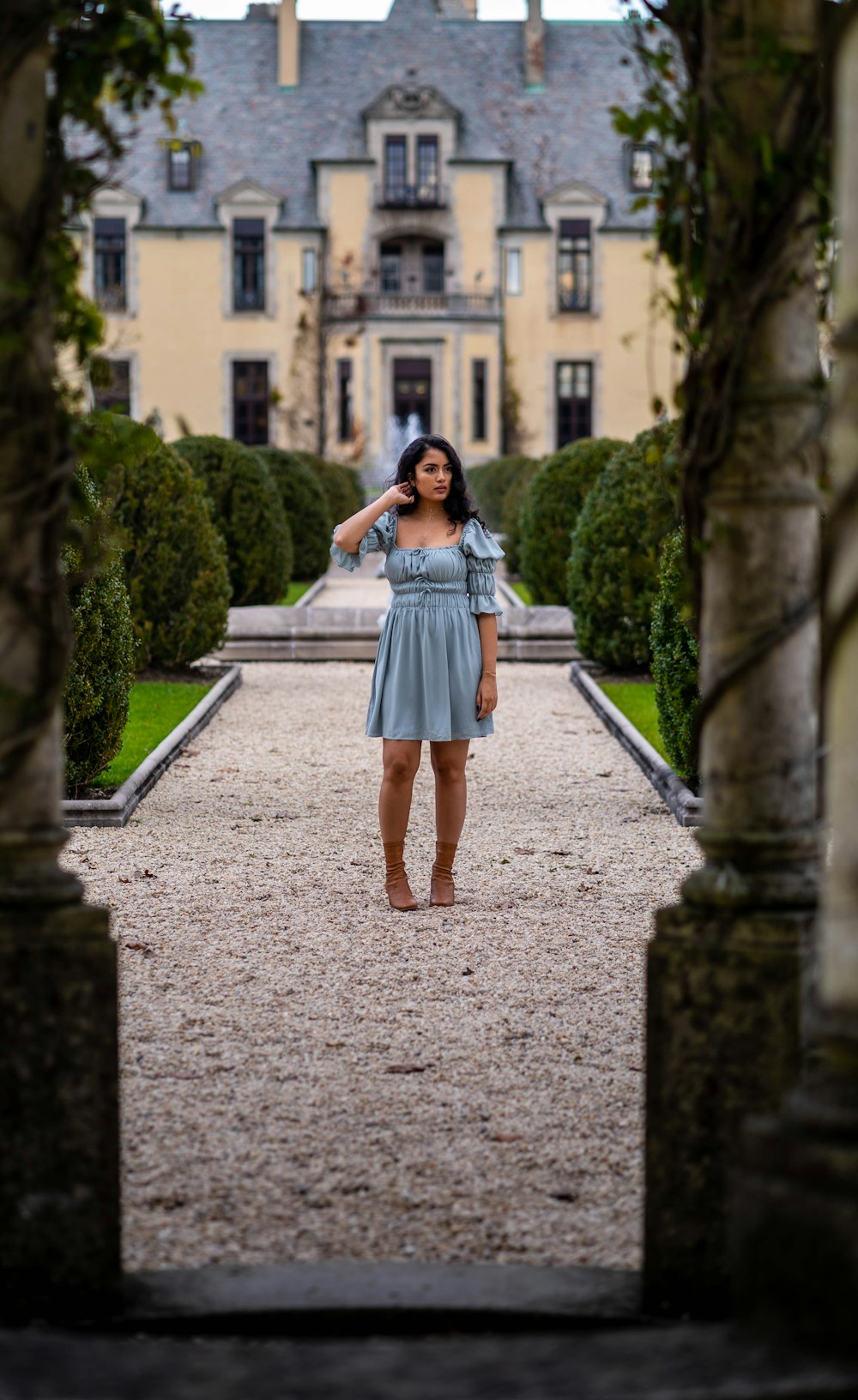 woman in blue dress standing on gray concrete pathway during daytime