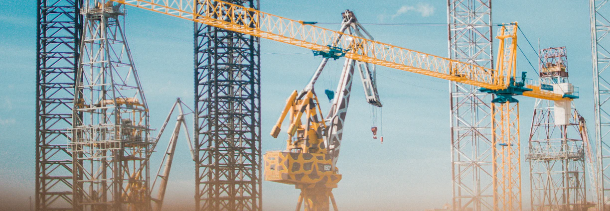 Modern construction site with cranes and workers collaborating under clear sky.