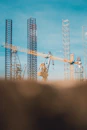 Industrial construction site showing cranes and workers collaborating under a clear sky.