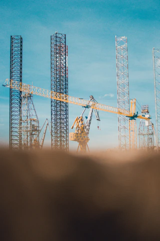 A modern construction site with workers and heavy machinery under a clear blue sky.