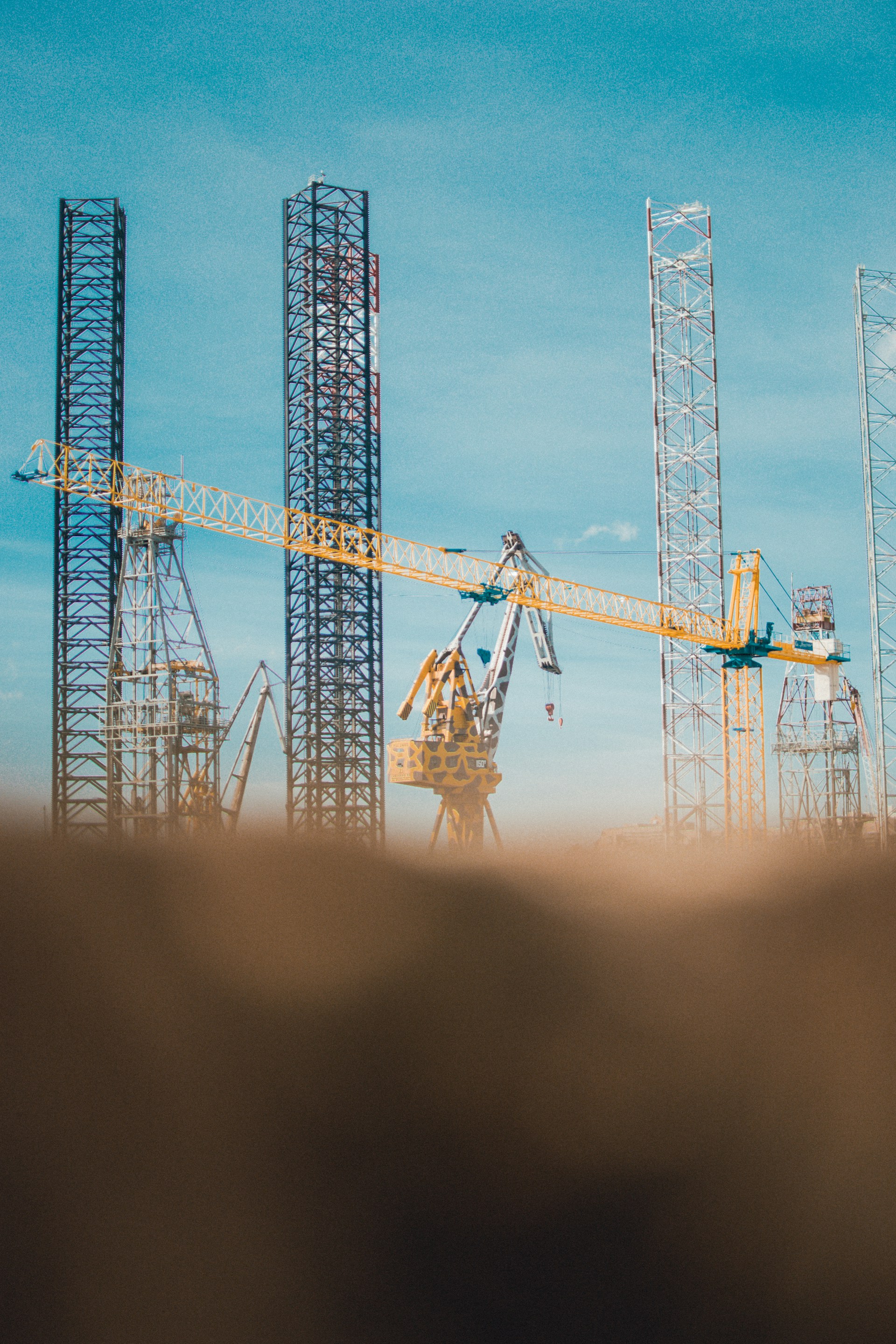 A serene construction site with cranes and scaffolding against a clear blue sky.