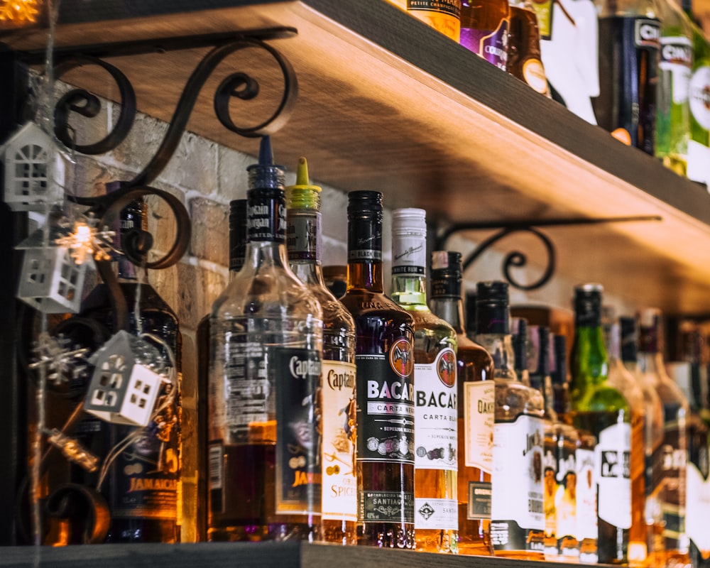 assorted glass bottles on brown wooden shelf