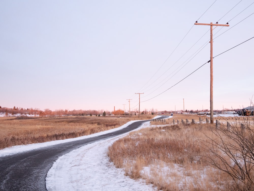 gray concrete road between brown grass field during daytime