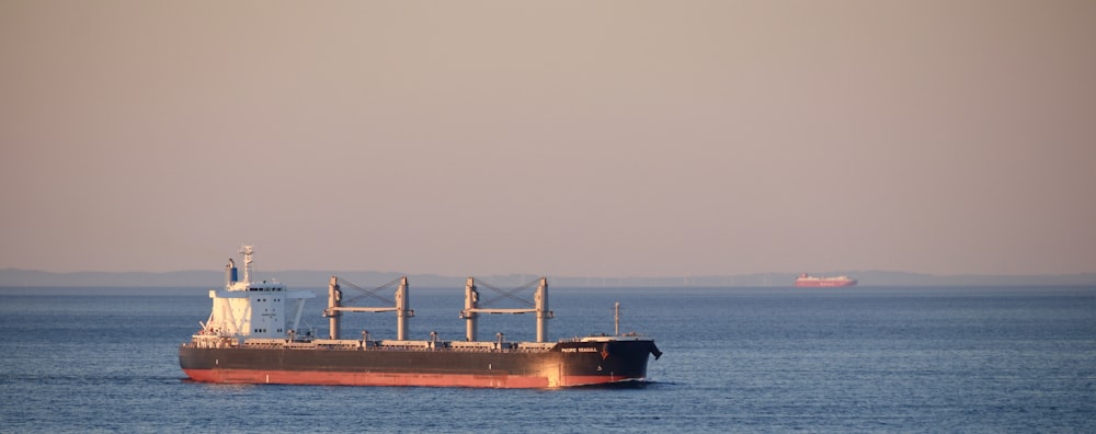 red ship on sea under gray sky during daytime